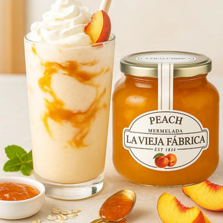 Glass of dessert with peach marmelade and a jar of Lavieja Fábrica peach marmelade on a light background.