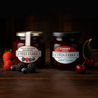 Two jars of La Vieja Fábrica marmalade and chutney on a wooden surface with fruits.