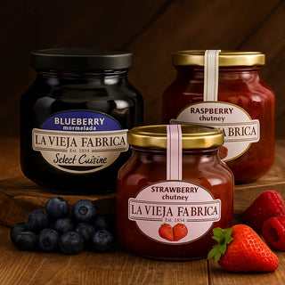 Three jars of La Vieja Fabrica Jams blueberries, raspberries, and strawberries on a wooden surface.